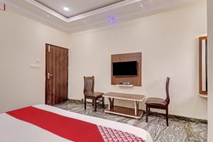a hotel room with a bed and a table and chairs at Super Collection O Ashraya Paradise in Bengaluru