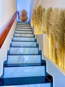 une cage d'escalier aux vitres bleues et une fresque d'arbres dans l'établissement Hoàng Nga 1 Homestay, à Phan Thiết