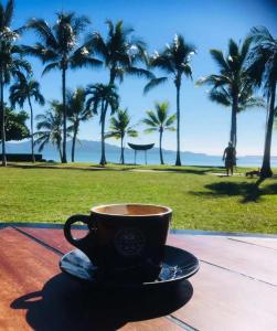 a cup of coffee sitting on a table with palm trees at 3BR Oceanfront Penthouse on The Strand, Townsville in North Ward +8 photos