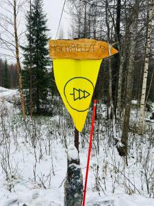 a yellow sign on a pole in the snow at "Mökki-Mélèze" chalet in Pallas-Yllastunturi, Levi in Kittilä