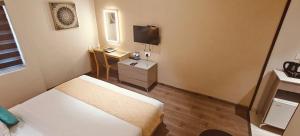 ティルプルにあるThe Mayberry -A Bergamont Group of Hotelsのベッドとテレビがあるホテルの部屋