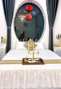 a bedroom with a white bed with a mirror at Hoàng Nga 1 Homestay in Phan Thiet