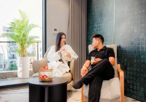 a man and a woman sitting in chairs in a room at X-Digital HOTEL in Bắc Ninh