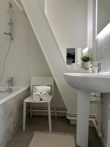 un bagno bianco con lavandino e vasca di L'Appartement du Forum - Reims centre Cathédrale a Reims