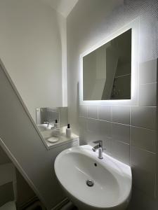 un bagno bianco con lavandino e specchio di L'Appartement du Forum - Reims centre Cathédrale a Reims Altre 13 foto