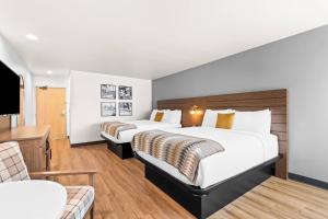 a hotel room with two beds and a couch at Maverick Hotel Eugene Near University, an Ascend Collection Hotel in Eugene