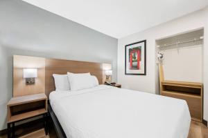 une chambre avec un grand lit blanc et une fenêtre dans l'établissement MainStay Suites Raleigh North, à Raleigh