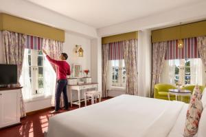 a man standing in a bedroom looking out the windows at Jetwing St Andrew's in Nuwara Eliya