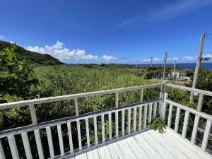 un paseo marítimo de madera con vistas a un campo en Shiawaseninaru Kourijima no Yado, en Nakijin