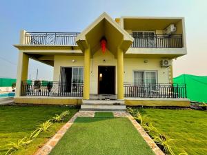 a yellow house with a balcony and a red ribbon at Staymist - Pool and Pause Villa in Nagaon
