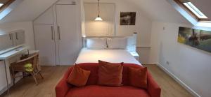 Un dormitorio con una cama grande y un sofá rojo. en The Coach House Studio Apartment, en Leamington Spa