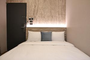 a bed with white sheets and blue pillows at Fun Stay Inn Hanzhong in Taipei