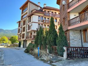 a large building with trees in front of a street at Murphys Lodge panorama apartment in Bansko