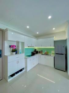 une grande cuisine avec des armoires blanches et un réfrigérateur dans l'établissement Minh Anh Apartment 3, à Thôn An Hòa