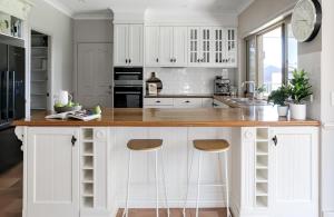 a kitchen with white cabinets and a counter with stools at Coastview Manor - Family Hinterland Retreat in Valdora