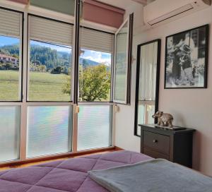 a bedroom with large windows and a bed with purple sheets at APARTAMENTO VALMAYOR in Potes