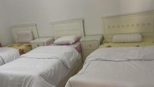 three beds in a room with white sheets at Turtles beach resort in Hurghada