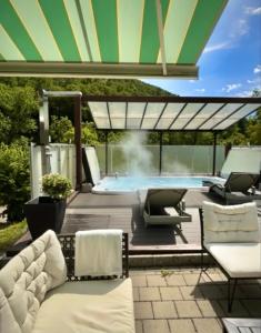 a patio with a swimming pool with chairs and an umbrella at Cozy Swiss Retreat - Scenic Swiss Villa Close to Bern & Interlaken in Frinvillier