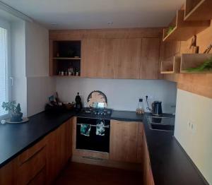 a kitchen with wooden cabinets and a black counter top at Lovely flat in a great location in Košice +6 photos