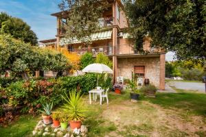 a house with an umbrella and a table and plants at Agriturismo Osea in Monteriggioni