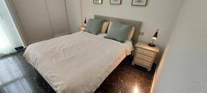 een kleine slaapkamer met een wit bed en een nachtkastje bij Mar 4 en Santa Pola in Santa Pola