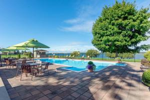 a swimming pool with chairs and a table and an umbrella at The Inn at Gran View Ogdensburg, an Ascend Collection Hotel in Ogdensburg