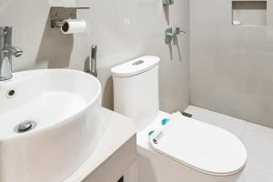 a white bathroom with a toilet and a sink at Urbanview Hotel JD Luxury Brebes in Banjararja