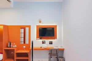 a room with a desk with a tv and a chair at Urbanview Hotel JD Luxury Brebes in Banjararja