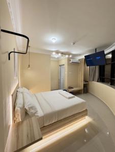 a bedroom with a white bed and a tv at Blenz Hotel in Serdang