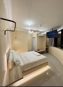 a bedroom with a white bed and a tv at Blenz Hotel in Serdang