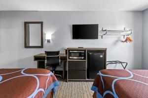 a hotel room with two beds and a desk with a tv at Rodeway Inn Delmont in Delmont