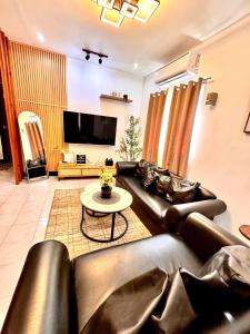 a living room with black leather couches and a tv at RKs Cozy Balai in General Santos