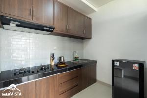 eine Küche mit Holzschränken und einem schwarzen Kühlschrank in der Unterkunft Amberley Hill Villa by Bukit Vista in Uluwatu