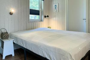 a white bed in a bedroom with a window at Schatzkiste - Dorf Ferienhaus 4a in Priwall