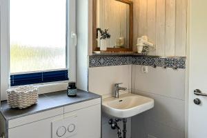 a white bathroom with a sink and a window at Schatzkiste - Dorf Ferienhaus 4a in Priwall +56 photos