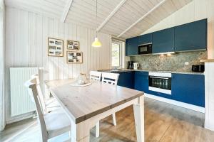 a kitchen with a wooden table and blue cabinets at Schatzkiste - Dorf Ferienhaus 18 in Priwall