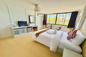 a bedroom with a large white bed and a television at Jomtien Wave Residence in Jomtien Beach