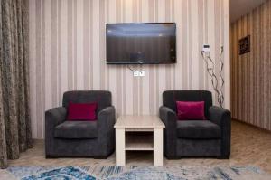 2 sillas y una mesa en la sala de estar con TV. en Sebail inn shah hotel and Shah hostel, en Baku