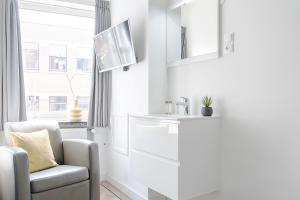 ティルブルフにあるCozy, Simple, And Affordable For Solo Travelerの椅子と洗面台のある白いリビングルーム