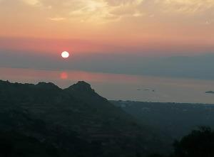 ein Sonnenuntergang, bei dem die Sonne über den Bergen untergeht in der Unterkunft YouGa Nest in Vívlos