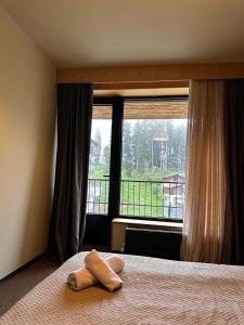 a stuffed animal sitting on a bed in front of a window at The 4th Floor Vista in front of Kokhta in Bakuriani