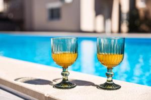 two glasses of wine sitting next to a swimming pool at Villa Lucy Apartments in Vir