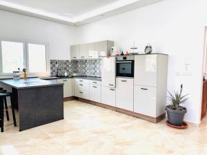 Peaceful Pool Villa في مراكش: مطبخ بخزائن بيضاء وطاولة عمل سوداء