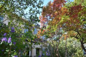 Un edificio con árboles y flores delante. en Le colibri bleu, en Argeliers