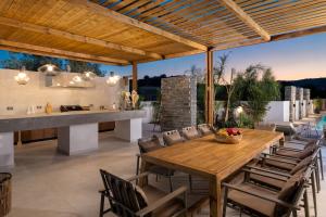 an outdoor kitchen and dining room with a wooden table and chairs at Lanik Luxury Pool Villa in Afantou