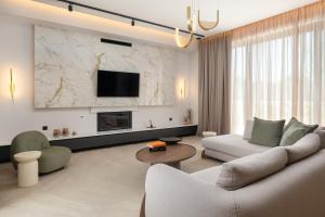 a living room with a white couch and a tv at Lanik Luxury Pool Villa in Afantou
