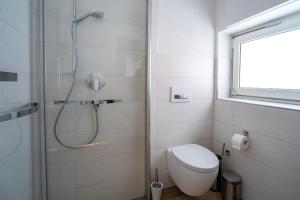 a white bathroom with a shower and a toilet at Ferienwohnung Agnes in Rappersweier +18 photos