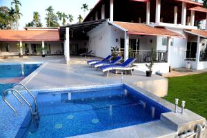 a swimming pool with blue chairs and a house at Tranquility Home Stay Coorg in Kutta