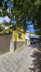 una casa amarilla en una calle de ladrillos junto a un edificio en Romantic House in Botanic Garden, en Banská Štiavnica