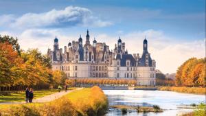 a large castle with a river in front of it at Maison Vallée du Loir in Saint-Rimay +2 photos